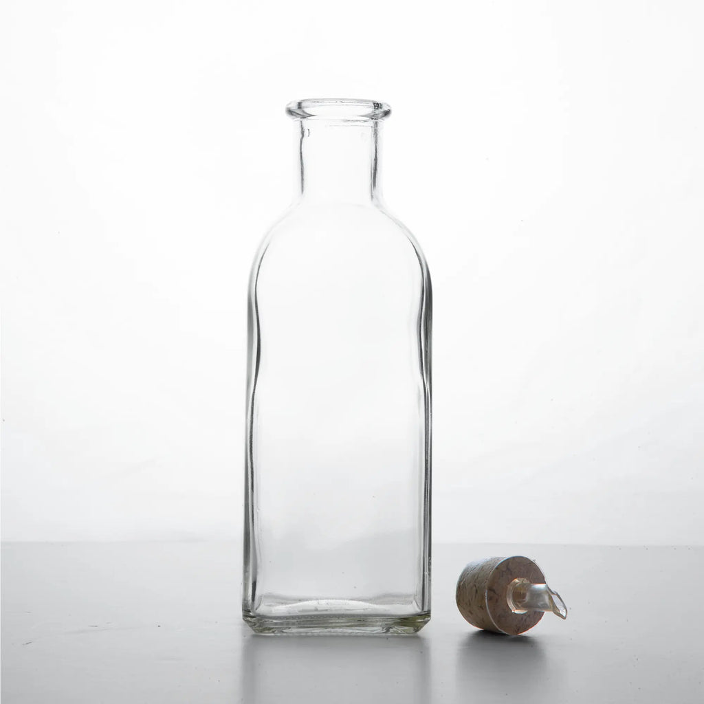 Klasyczna hiszpańska butelka 500 ml na oliwę 'frasca', pusta, korek leżący na blacie, zdjęcie przodem