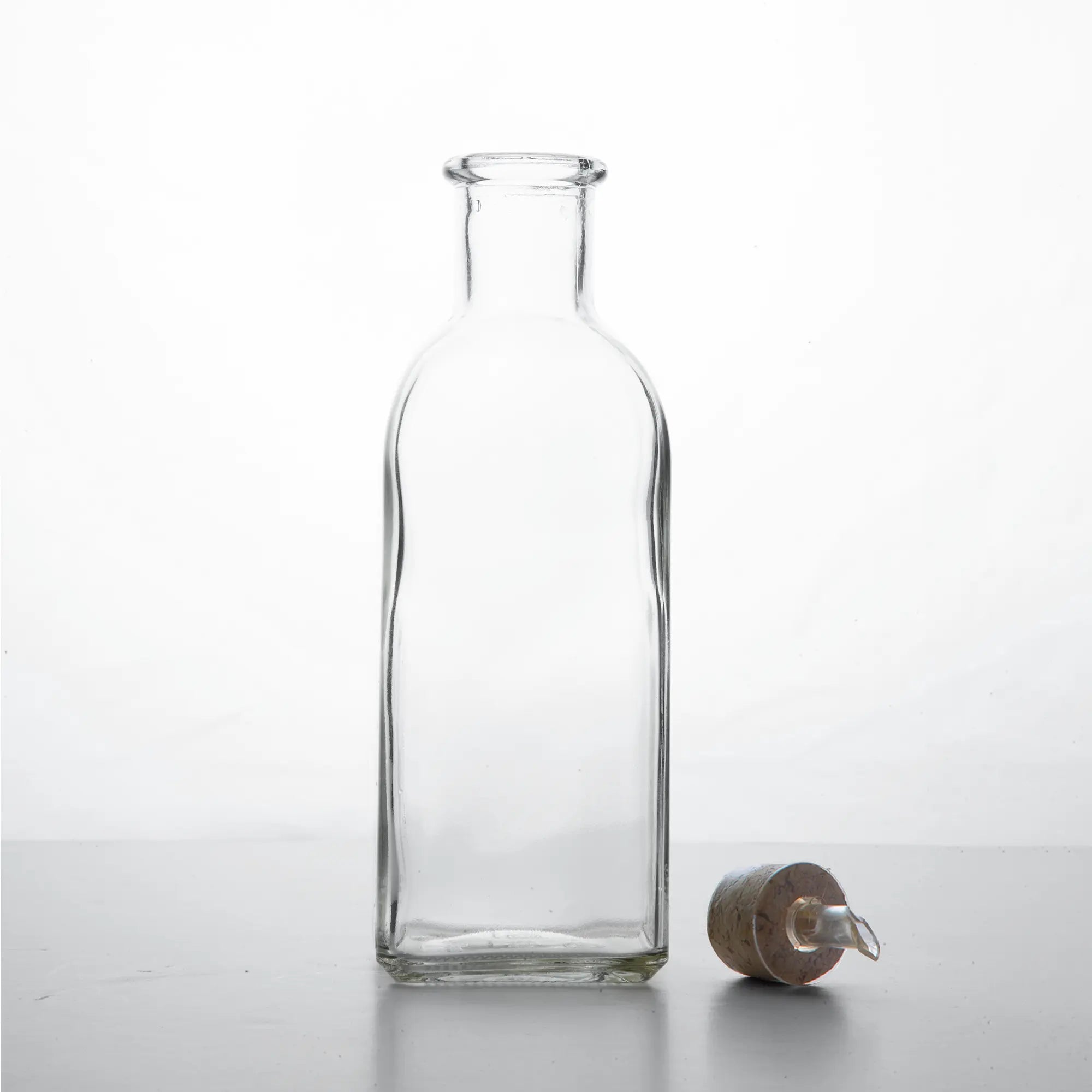Klasyczna hiszpańska butelka 500 ml na oliwę 'frasca', pusta, korek leżący na blacie, zdjęcie przodem